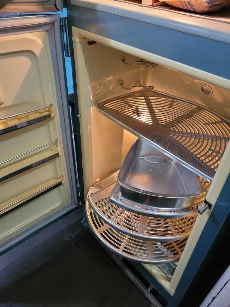 Interior of a 1950s General Electric refrigerator with circular revolving aluminum shelves and a stamped MEATS pan